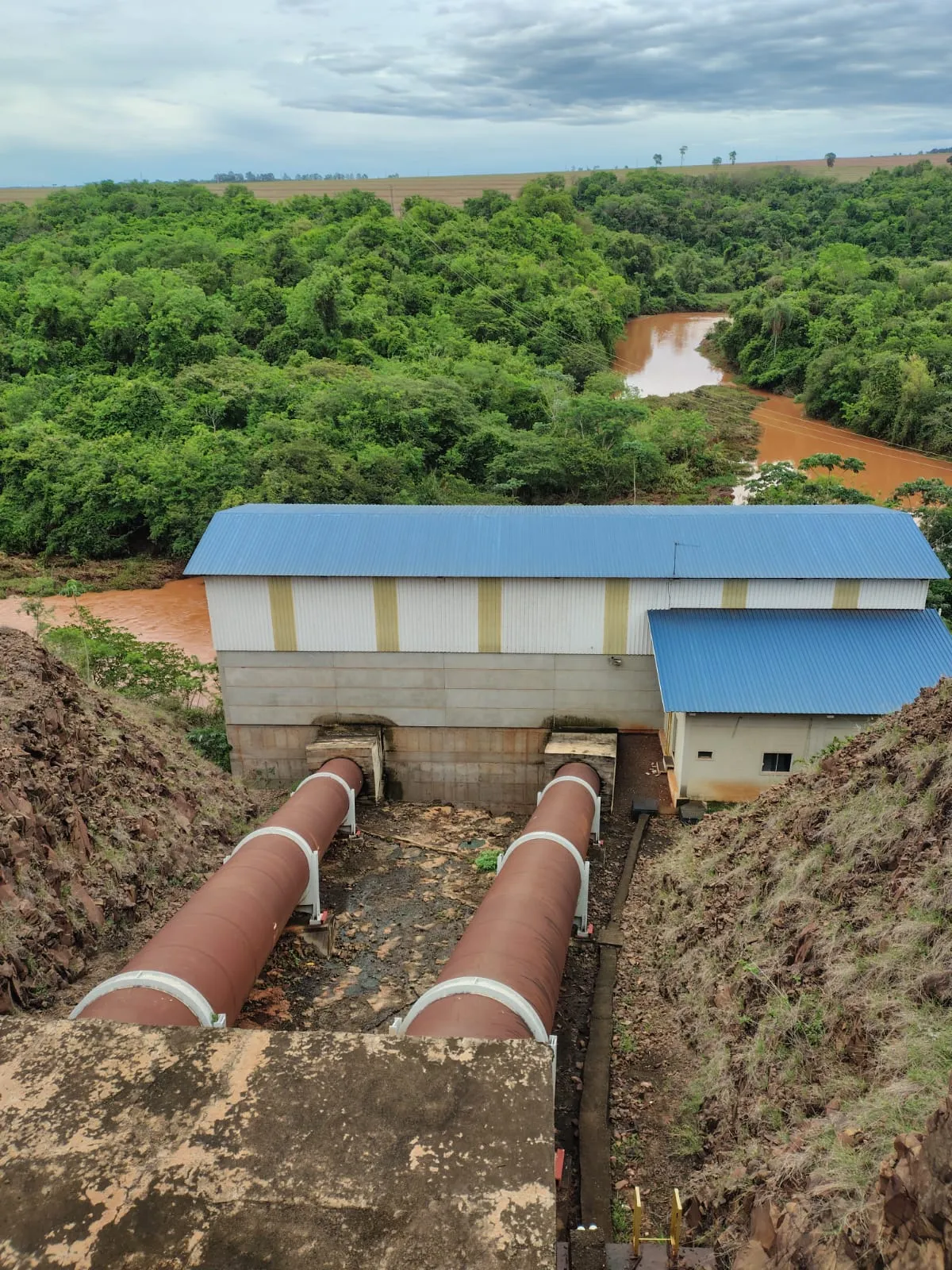 Estrutura industrial com grandes tubulações junto ao rio