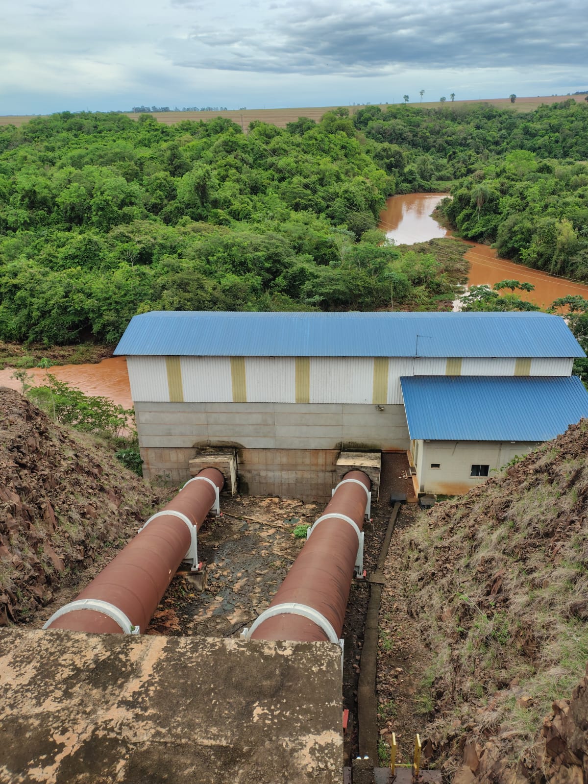 Estrutura industrial com tubulações de grande porte próximas ao rio